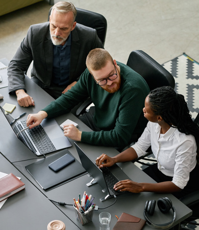 A group of three people sitting down and engaging in a project
